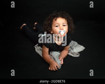 Ritratto orizzontale di una bella gara mista di 2 anni e mezzo ragazzo succhiando un capezzolo Foto Stock