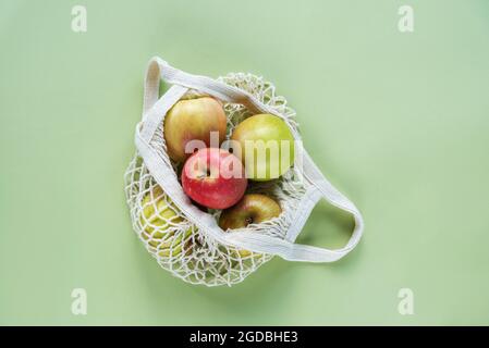 Mele mature fresche in un sacchetto a corda su sfondo verde. Zero sprechi, nessun concetto di plastica. Vista dall'alto, disposizione piatta. Foto Stock