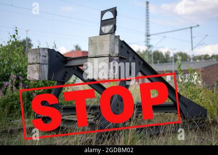 Blocco buffer alla fine di una pista ferroviaria con testo Stop, concetto di sciopero o smantellamento di linee ferroviarie, fuoco selezionato Foto Stock