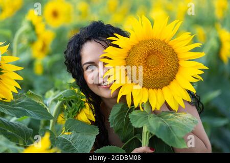 Ritratto di una bella donna sorridente dai capelli scuri con un grande girasole in mano Foto Stock