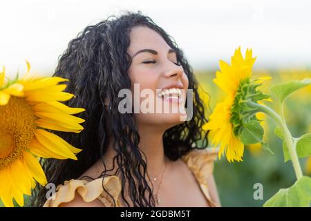 Ritratto di una bella donna sorridente dai capelli scuri con un grande girasole in mano Foto Stock