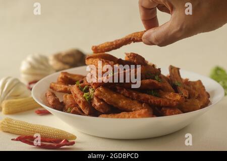 Frittelle croccanti fritte di mais per neonati o di mais per neonati preparate con un granoturco per bambini cotto a vapore immerso in una pastella di farina piccante. Una ricetta di base. Scatto su bianco Foto Stock