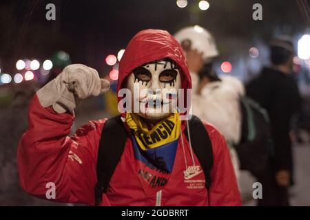 Bogotà, Colombia. 11 Agosto 2021. Un dimostratore con bandiera colombiana alza il suo pugno mentre gli scontri aumentano tra i dimostranti e la polizia in rivolta della Colombia (ESMAD) nel nord di Bogotà, Colombia, adnistano lo sfratto e la deforestazione di una riserva naturale il 11 agosto 2021. Credit: Long Visual Press/Alamy Live News Foto Stock