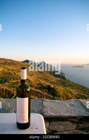 Tramonto su una tranquilla isola greca. Mentre la luce svanisce, è il momento di rilassarsi con un buon vino e una vista spettacolare sul mare Egeo. Foto Stock