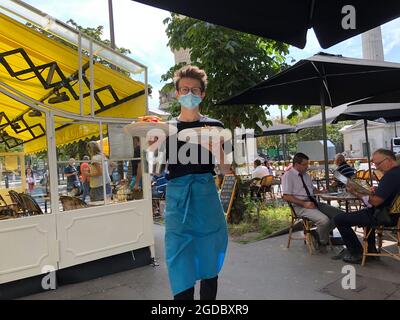 Parigi, Francia, adolescente cameriere adolescente con maschera Covid, lavoro al ristorante bistrot francese, 'Chez Prosper' che tiene piatti all'aperto sulla terrazza, ristorante contemporaneo Foto Stock