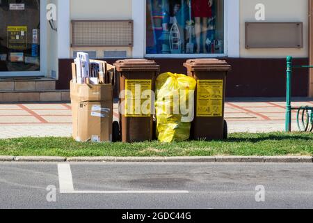 Contenitori separati per il riciclaggio e sacchetti di carta e rifiuti di plastica in strada, Sarvar, Ungheria Foto Stock