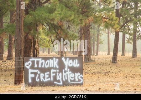 12 AGOSTO 2021 - JANESVILLE, CALIFORNIA, STATI UNITI. Un cartello di fronte ad una residenza esprime apprezzamento per i vigili del fuoco mentre il fumo riempie l'aria. Foto Stock