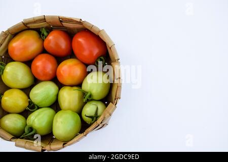 Tre tipi diversi di pomodori: Pomodoro verde, giallo, rosso in un cestino su sfondo bianco Foto Stock