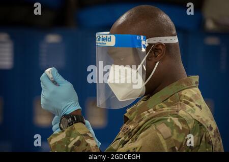 Lo staff dell'esercito degli Stati Uniti Sgt. Donnell Niles, 192nd Engineer Battaglione medic, disegna il vaccino moderno COVID-19 da un flaconcino in una siringa alla Bradley Air National Guard base a East Granby, Connecticut, 2 gennaio 2021. La Guardia Nazionale del Connecticut ha iniziato a somministrare il vaccino in conformità con il piano di distribuzione del vaccino COVID-19 del Dipartimento della Difesa, con dosi volontariamente somministrate a soldati e Airmen in prima linea della risposta pandemica COVID-19. (STATI UNITI Air National Guard foto di staff Sgt. Steven Tucker) Foto Stock