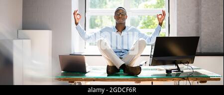 Dipendente africano che fa salute mentale meditazione Yoga in ufficio Foto Stock