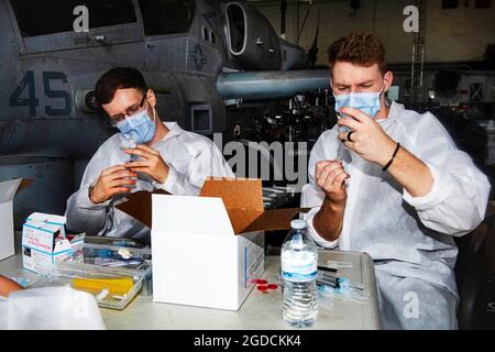 OKINAWA, Giappone (Feb 14, 2021) Ospedale Corpsmen Dillon Bothell, sinistra e Devin Declercq preparare COVID-19 vaccinazioni a bordo della nave da carico anfibia USS New Orleans (LPD 18). New Orleans, parte dell'America Expeditionary Strike Group, insieme alla 31st Marine Expeditionary Unit, opera nell'area di responsabilità della settima flotta statunitense per migliorare l'interoperabilità con alleati e partner e fungere da forza di risposta pronta per difendere la pace e la stabilità nella regione dell'Indo-Pacifico. (STATI UNITI Foto Navy di Mass Communication Specialist 2nd Class Kelby Sanders) Foto Stock