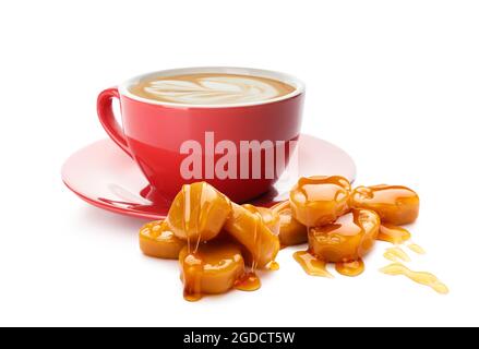 Tazza di gustoso cappuccino con caramelle al caramello su sfondo bianco Foto Stock