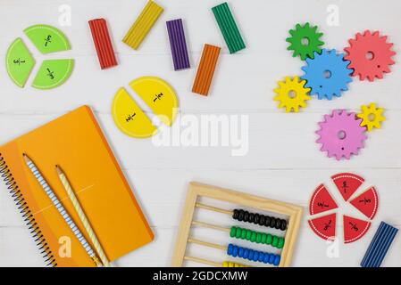 Frazioni multicolore, blocchi, taccuino su tavola di legno bianco. Ritorno a scuola, matematica divertente, giochi per l'asilo, istruzione prescolare. Foto Stock
