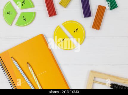 Frazioni multicolore, blocchi, taccuino su tavola di legno bianco. Ritorno a scuola, matematica divertente, giochi per l'asilo, istruzione prescolare. Foto Stock