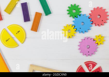Frazioni multicolore, blocchi, taccuino su tavola di legno bianco. Ritorno a scuola, matematica divertente, giochi per l'asilo, istruzione prescolare. Foto Stock