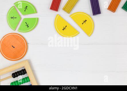 Frazioni multicolore, blocchi, taccuino su tavola di legno bianco. Ritorno a scuola, matematica divertente, giochi per l'asilo, istruzione prescolare. Foto Stock