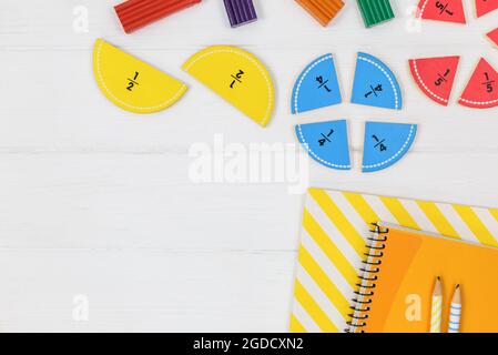 Frazioni multicolore, blocchi, taccuino su tavola di legno bianco. Ritorno a scuola, matematica divertente, giochi per l'asilo, istruzione prescolare. Foto Stock