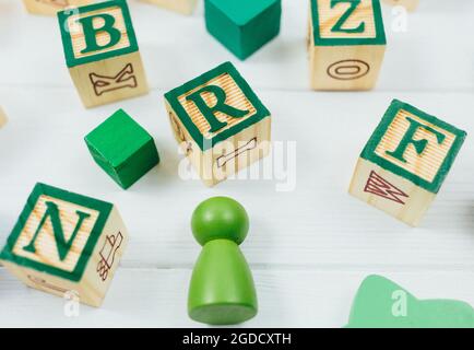 Blocchi di alfabeto di legno verde su un tavolo di legno bianco. Ritorno a scuola, giochi per asilo, istruzione prescolare. Foto Stock