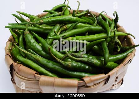 Peperoncini piccanti e piccanti di colore verde scuro appena rapiti in cestino. Raccolta di peperoni verdi organici in cesto di vimini Foto Stock
