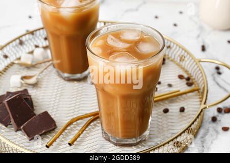 Vassoio con bicchieri di gustoso caffè ghiacciato e pezzi di cioccolato sul tavolo Foto Stock