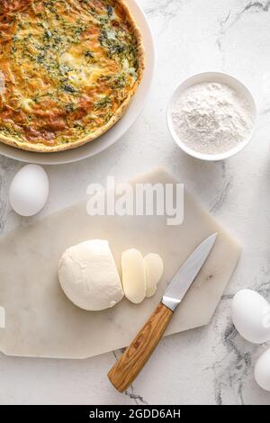 Crostata di spinaci e ingredienti su sfondo chiaro Foto Stock