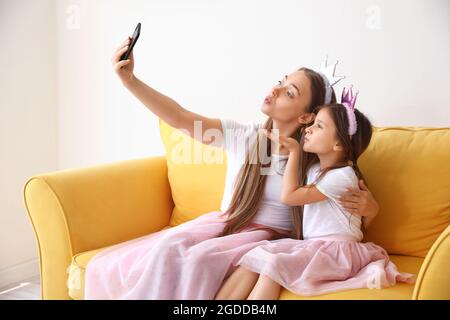 Giovane donna e sua figlia piccola che prende selfie a casa Foto Stock