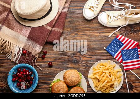 Telaio fatto di bandiere americane con cibo tradizionale, vestiti e plaid su sfondo di legno Foto Stock