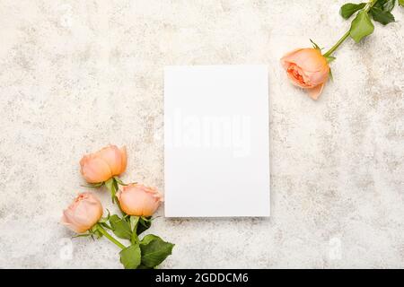 Foglio di carta bianco e belle rose di pony su sfondo chiaro Foto Stock