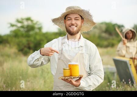 Apicoltore con miele in vasi all'apiario Foto Stock