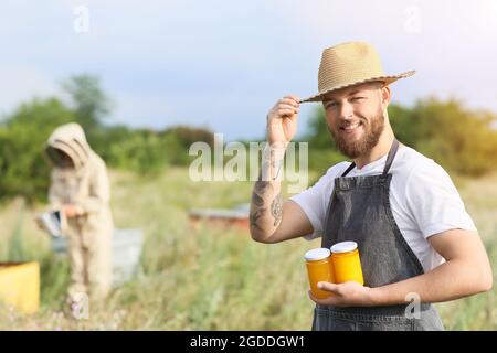 Apicoltore con miele in vasi all'apiario Foto Stock