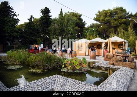 Sitges, Spagna. 13 Agosto 2021. La gente cena al Gastro Village Area del Jardins de Terramar Festival a Sitges. Ogni anno la città di Sitges (Barcellona, Spagna) ospita il Festival Jardins de Terramar, dove cantanti internazionali si esibiscono dal vivo. Ore prima di ogni concerto, i visitatori possono gustare cucina mediterranea, vini e cavas (Champagne della regione della Catalogna) presso il Gastro Village in un'atmosfera rilassata nella sua zona Chill out. Si tengono spettacoli musicali per intrattenere il pubblico. Credit: SOPA Images Limited/Alamy Live News Foto Stock