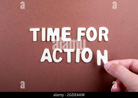 È tempo di agire. Lettere bianche in legno con testo su sfondo marrone. Foto Stock