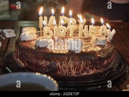 Torta con l'iscrizione buon compleanno con candele brucianti. Foto Stock