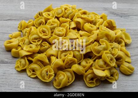 Tortellini freschi crudi su tavola di legno. Cucina italiana Foto Stock