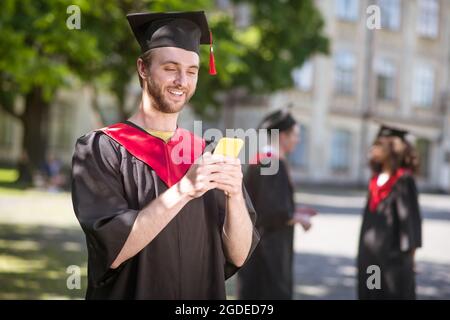 Tall felice graduate testando e guardando eccitato Foto Stock