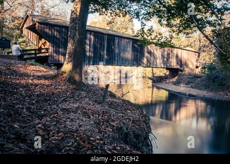 Woodbury, Georgia, USA- 14 novembre 2020: Lunga esposizione dello storico Red Oak Creek Covered Bridge costruito intorno al 1840 da Horace King e il sottostante ponte Foto Stock