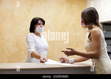 Carta per la firma del cliente presso il banco della reception in maschera facciale Foto Stock