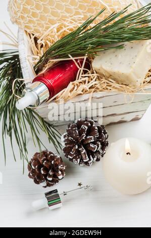 Prodotti di bellezza e cosmetici con decorazione natalizia e composizione di candela illuminata in cestino di legno bianco shabby Foto Stock