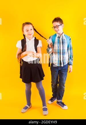 Il carino ragazzino tira la treccia della studentessa Foto Stock