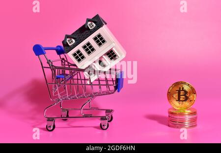 Acquisto di proprietà con Bitcoin Pagamenti. Concetto di acquisto di immobili e case per criptovaluta. Moneta e carrello della casa e dello shopping BTC. Foto Stock