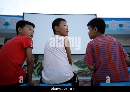 (210813) -- TAIYUAN, 13 agosto 2021 (Xinhua) -- i bambini aspettano di vedere un film all'aperto nel villaggio di Gaojiayan, Sanjiao Township della contea di Liulin, nella provincia di Shanxi della Cina del nord, 10 agosto 2021. Nel 1975, Sanjiao Township fondò un team di proiezione cinematografica. Liu Bufei e Liu Dengzhao, entrambi cinefili fin dall'infanzia, si unirono alla squadra e divennero proiettisti rurali. Nel 2007, la squadra divenne una troika con l'ingresso del proiettile di seconda generazione Xue Xiaogang, che aveva visto film all'aperto nel villaggio mentre era cresciuto. Nel corso degli anni, il team di proiezione, per innumerevoli volte ha guidato alon Foto Stock