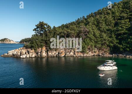 Vista su un piccolo yacht a motore che naviga sul mare e sull'isola mediterranea sullo sfondo. Vacanze estive Foto Stock