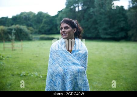 Metà donna adulta in piedi in campo rurale avvolto in una coperta, ritratto Foto Stock