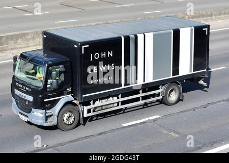 Vista frontale e dall'alto di John Lewis & Partners Retail Consumer Business Transport Delivery camion e cabina con conducente che viaggia lungo l'autostrada del Regno Unito Foto Stock