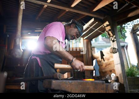 Fabbro lavora nella sua fucina Foto Stock