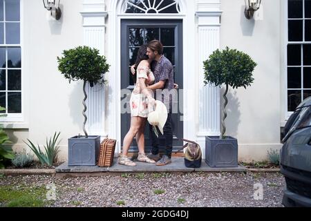 Coppia romantica che abbraccia ogni altra al hotel porta anteriore Foto Stock