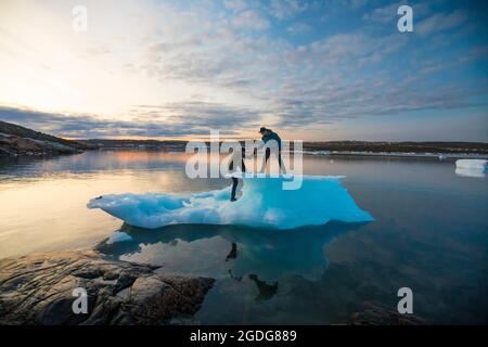 Gli amici si aiutano l'un l'altro su un iceberg. Foto Stock