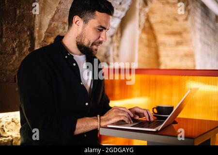 Un uomo d'affari felice che usa un computer portatile al bar Foto Stock