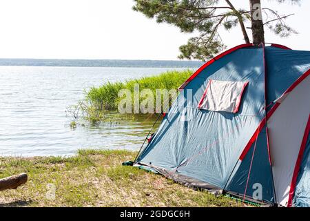 Tenda sulla riva del lago sul bordo della foresta Foto Stock