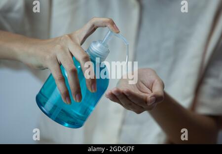 Le mani di una giovane donna spruzzano un gel igienizzante per le mani per pulire le mani dai batteri Foto Stock